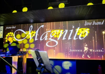 DJ пултът пред екрана с надпис Magnito piano bar live band